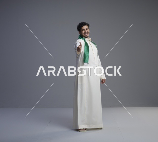 رجل سعودي بالثوب والوشاح الوطني يصافح بابتسامة