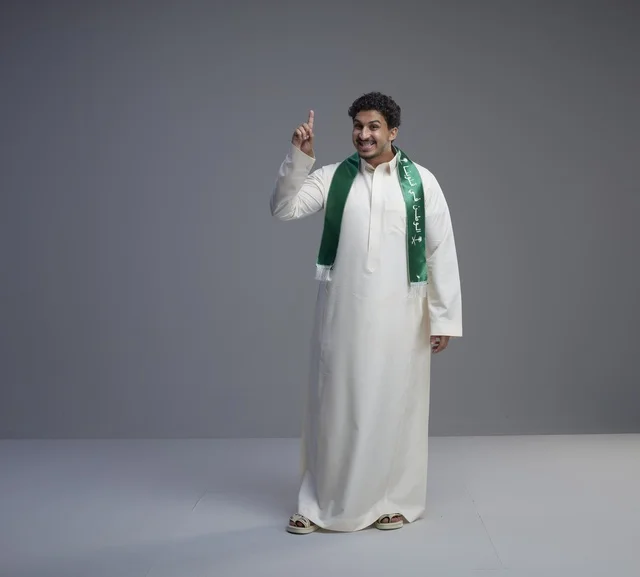 شاب سعودي بالوشاح الوطني يشير بإصبعه للأعلى