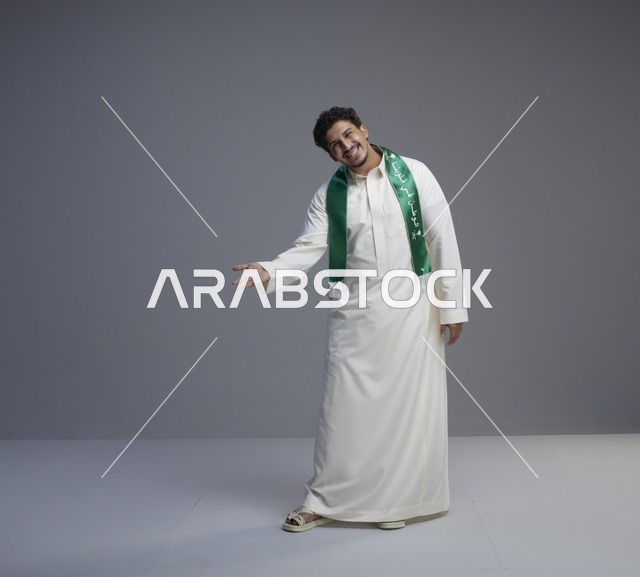 شاب سعودي يرتدي الثوب التقليدي والوشاح الوطني الأخضر