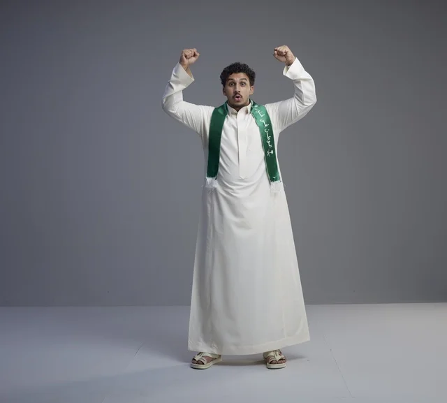 شاب سعودي بوشاح وطني يحتفل في الاستوديو