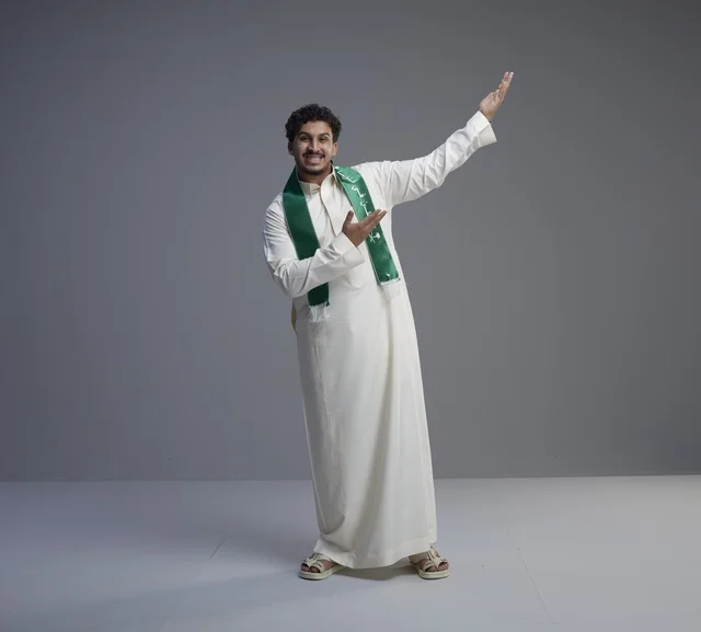 شاب سعودي بوشاح وطني بوضعية العرض والترحيب
