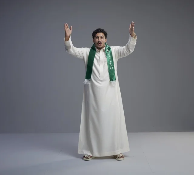 شاب سعودي يحتفل باليوم الوطني بالثوب والوشاح الأخضر
