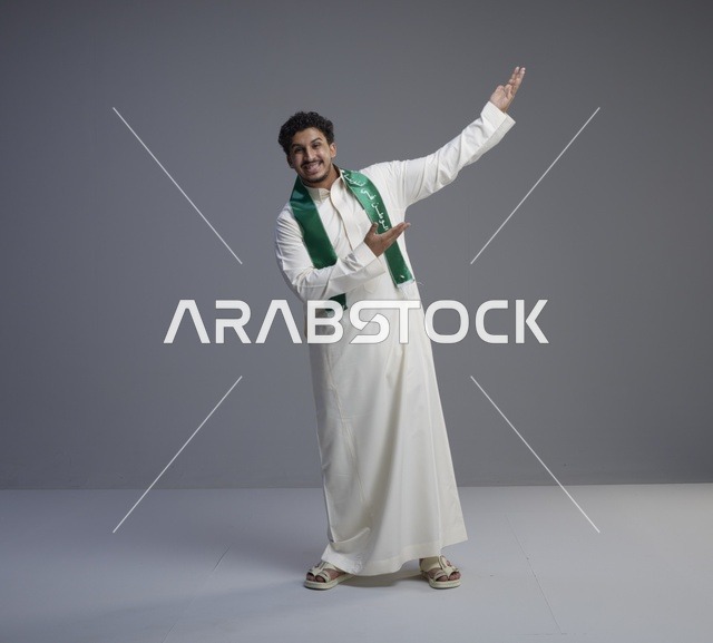 شاب سعودي بالثوب والوشاح الوطني يشير لجهة اليمين