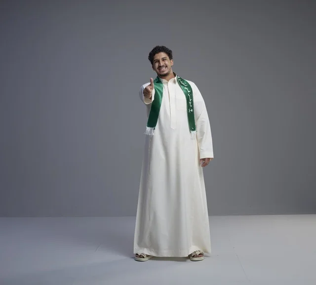 شاب سعودي بالثوب التقليدي والوشاح الوطني الأخضر