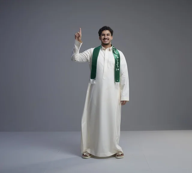 شاب سعودي يرتدي وشاح اليوم الوطني السعودي في استوديو