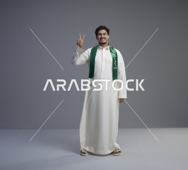 شاب سعودي يرتدي الثوب والوشاح الوطني السعودي الأخضر