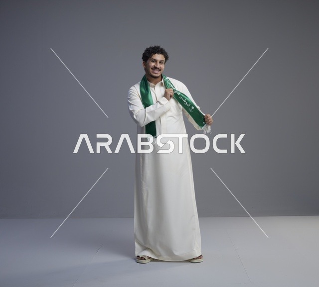 شاب سعودي بالثوب الأبيض والوشاح الوطني الأخضر