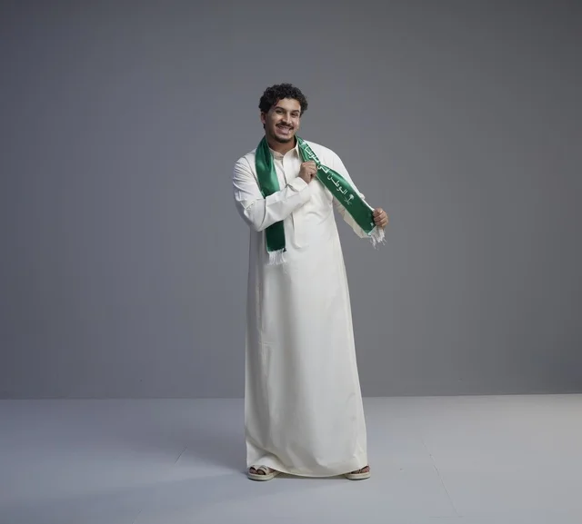 شاب سعودي بالثوب الأبيض والوشاح الوطني الأخضر