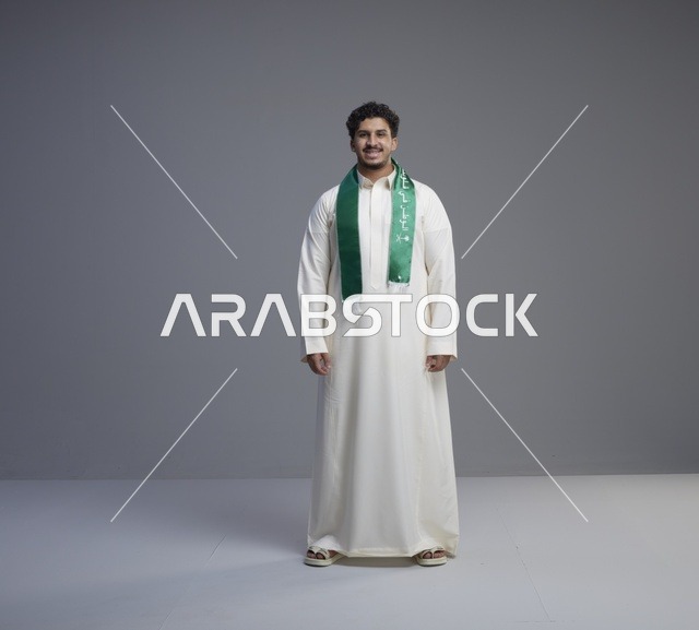 شاب سعودي بالثوب والوشاح الوطني الأخضر في الاستوديو