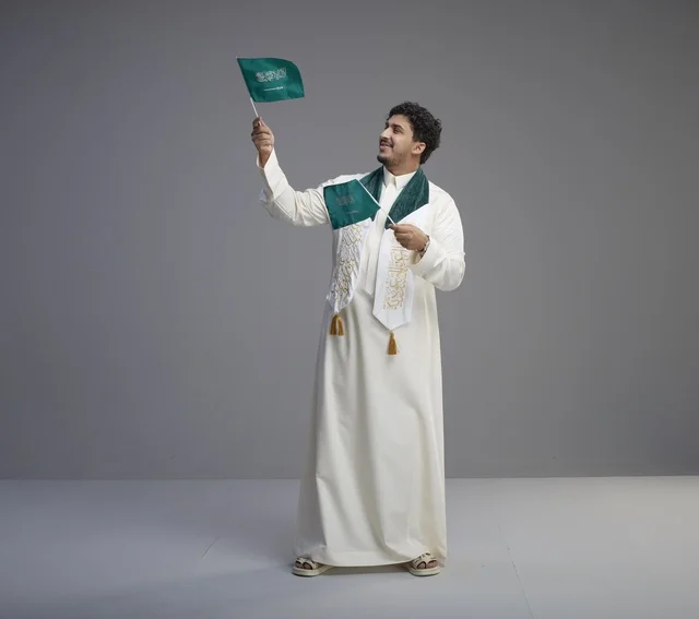 خريج سعودي يحمل العلم الوطني السعودي في الاستوديو