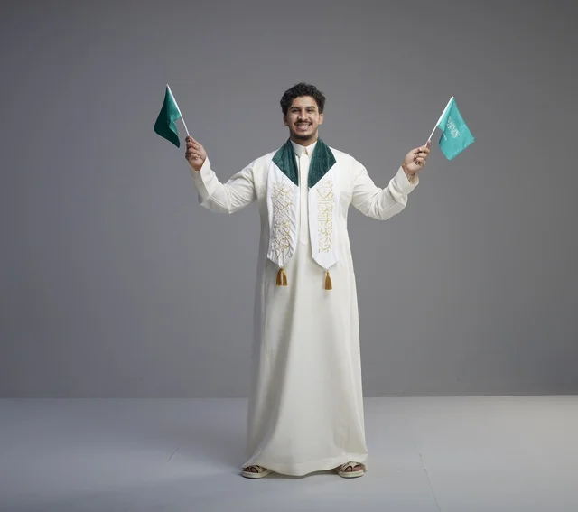 خريج سعودي يحمل الأعلام الوطنية في الاستوديو