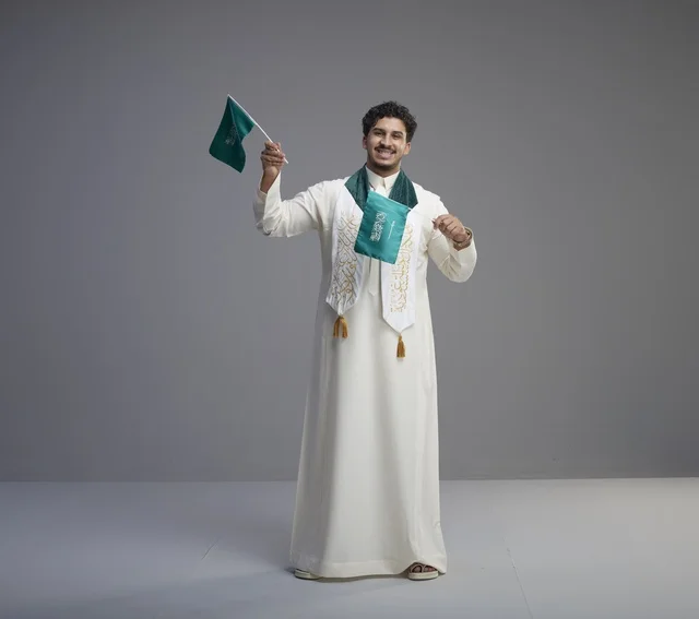 خريج سعودي يحتفل بالعلم الوطني بالثوب التقليدي