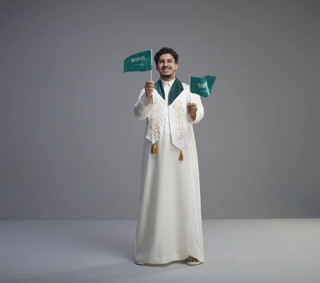 خريج سعودي يحمل العلم الوطني في الاستوديو