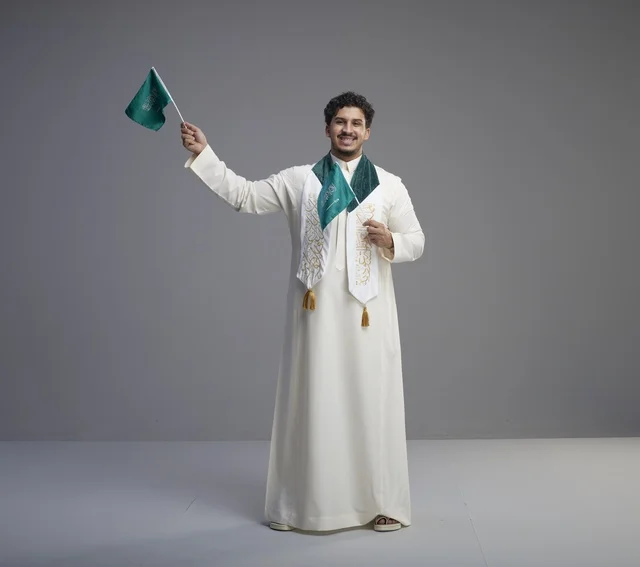 خريج سعودي يحمل العلم الوطني في الاستوديو