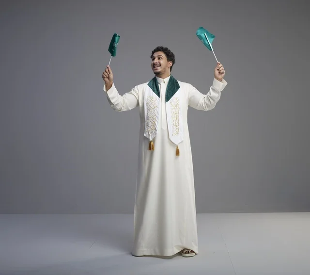 خريج سعودي يحمل الأعلام الوطنية في الاستوديو
