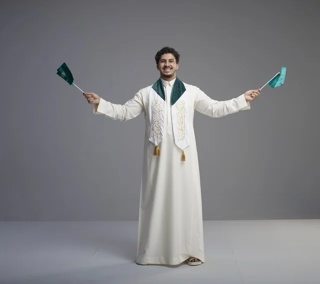 خريج سعودي يحتفل بالأعلام الوطنية في الاستوديو