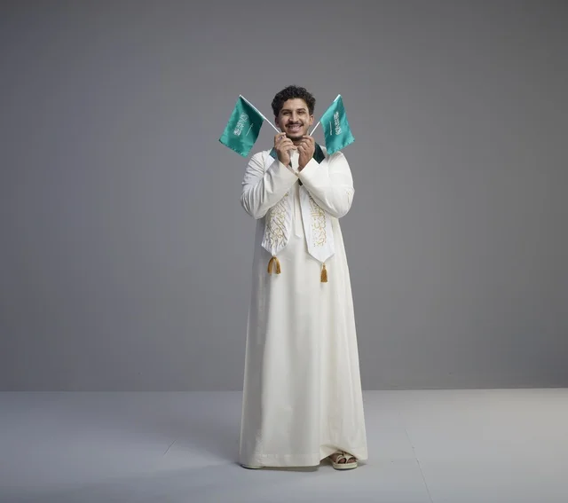 Saudi Male Graduate Holding National Flags in Studio