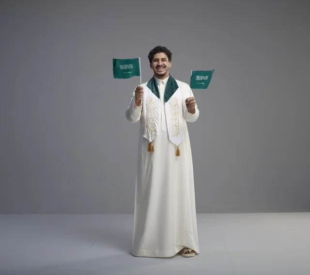خريج سعودي يحمل الأعلام الوطنية في الاستوديو
