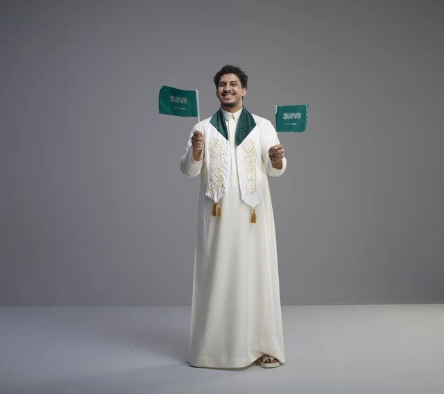 خريج سعودي يحمل الأعلام الوطنية في استوديو