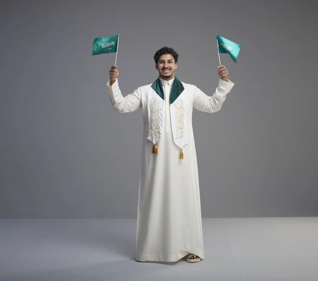 خريج سعودي يحمل العلم الوطني في الاستوديو