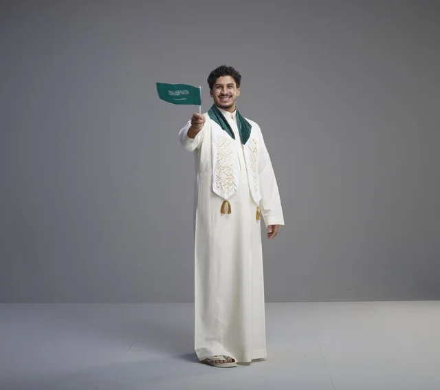 خريج سعودي يحمل العلم الوطني في الاستوديو