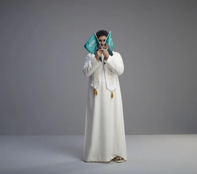 Saudi Male Graduate Holding National Flags in Studio