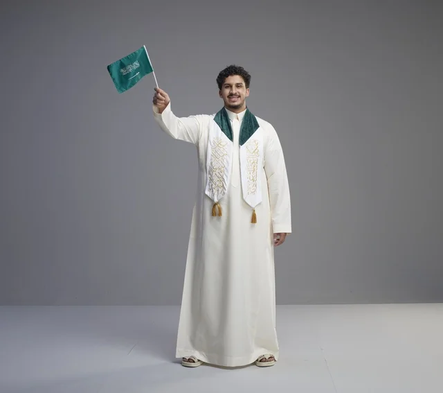 خريج سعودي يحمل العلم الوطني في الاستوديو