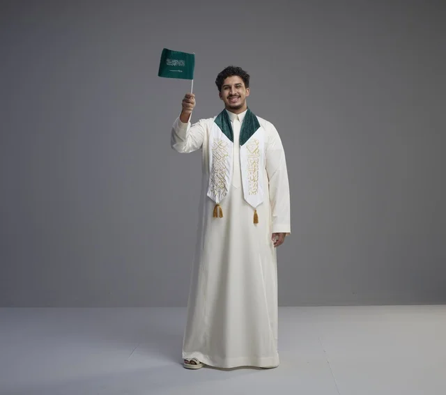 خريج سعودي يحمل العلم الوطني في الاستوديو
