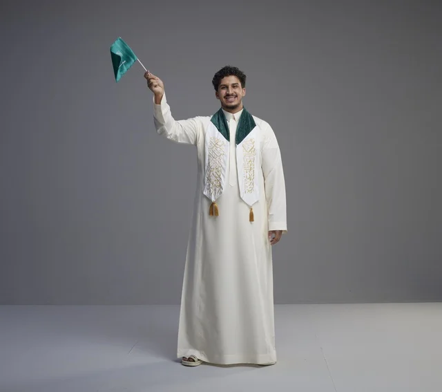 خريج سعودي يحمل العلم الوطني في الاستوديو