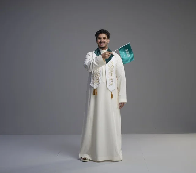 خريج سعودي يحمل العلم الوطني السعودي في الاستوديو