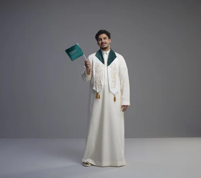 خريج سعودي بالثوب التقليدي يحمل العلم الوطني