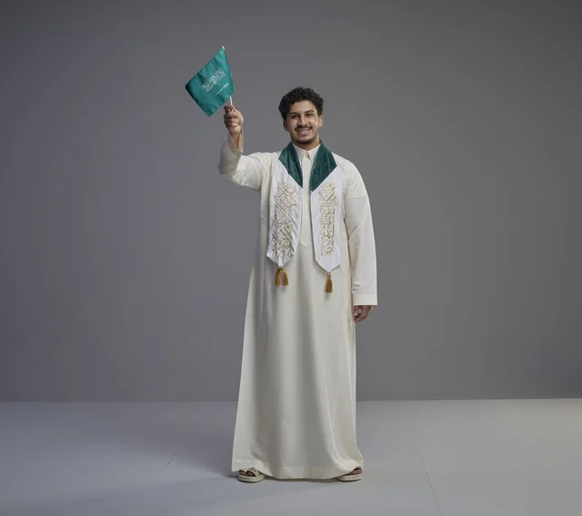 خريج سعودي يحمل العلم الوطني في الاستوديو