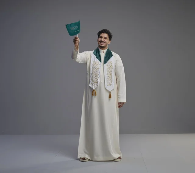 خريج سعودي يحمل العلم الوطني في الاستوديو