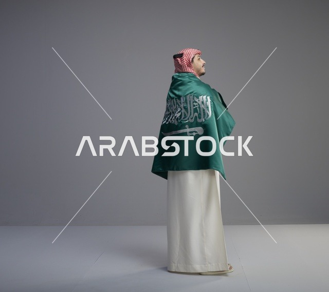 رجل سعودي يلتف بالعلم الوطني السعودي في الاستوديو