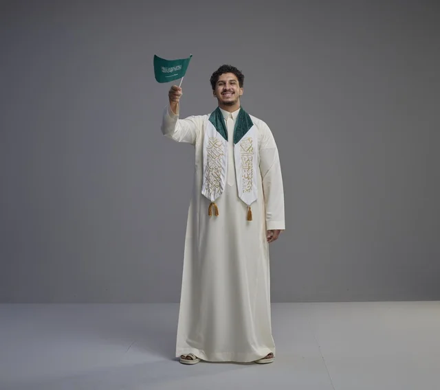 خريج سعودي يحمل العلم الوطني في الاستوديو