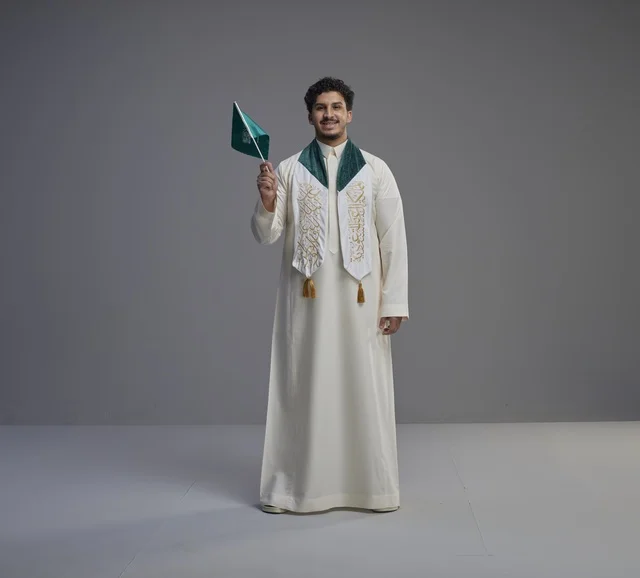خريج سعودي يحمل العلم الوطني بوشاح التخرج في الاستوديو