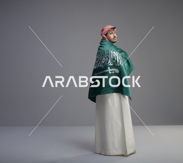 رجل سعودي يلتف بعلم السعودية في الاستوديو