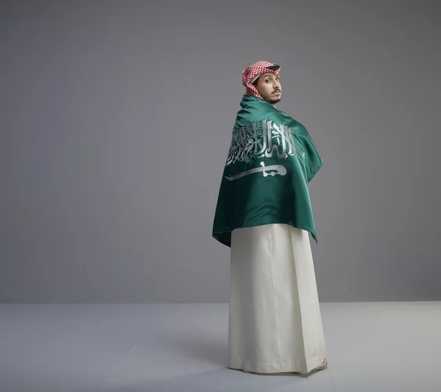 رجل سعودي يلتف بعلم السعودية في الاستوديو