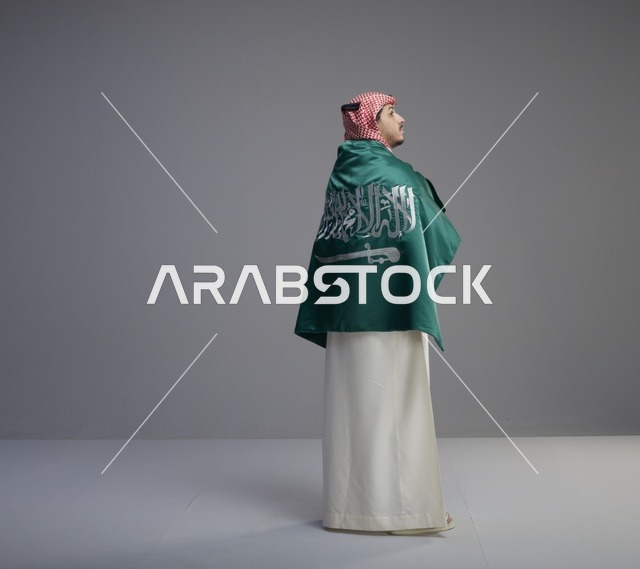 رجل سعودي بالعلم الوطني بالزي التقليدي