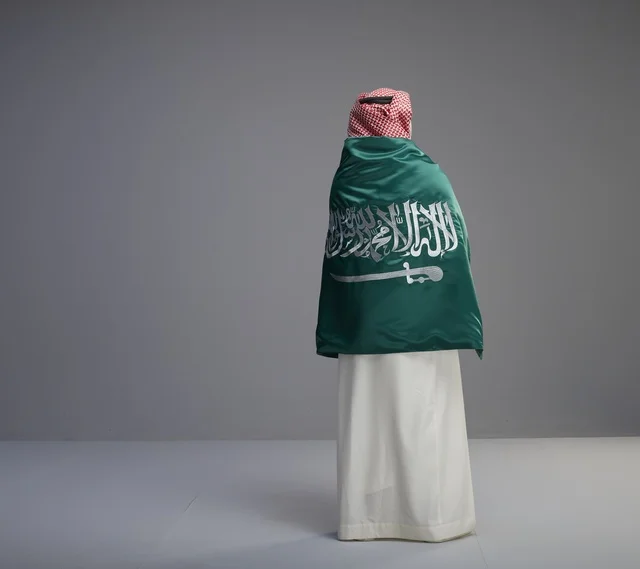 رجل سعودي يلتف بالعلم الوطني من الخلف