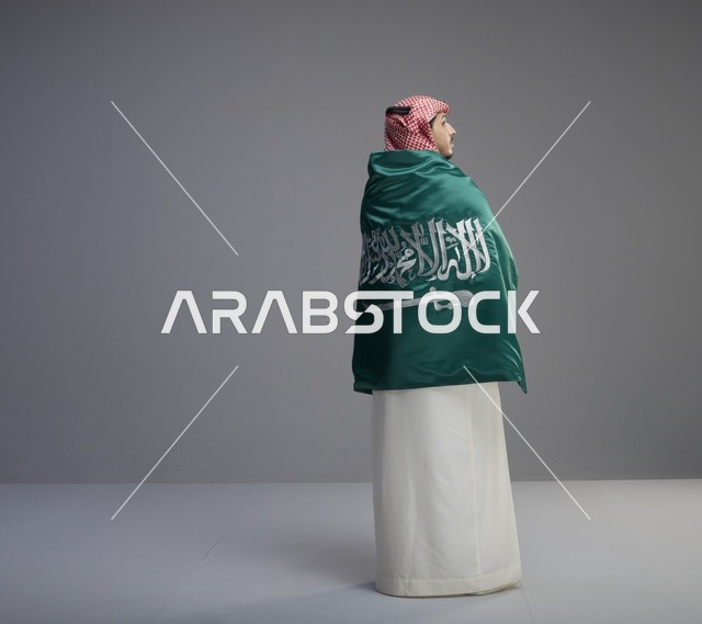 رجل سعودي يلتف بعلم السعودية في الاستوديو