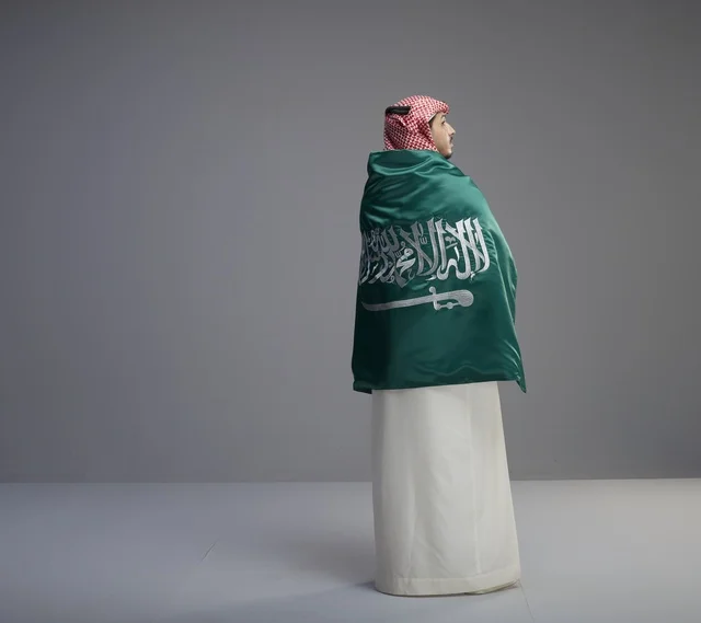 رجل سعودي يلتف بعلم السعودية في الاستوديو
