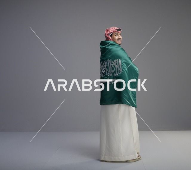 Saudi Man Wrapped in Saudi Flag on Grey Background