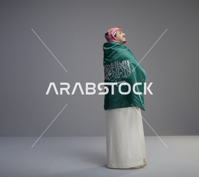 رجل سعودي يلتف بعلم السعودية في الاستوديو