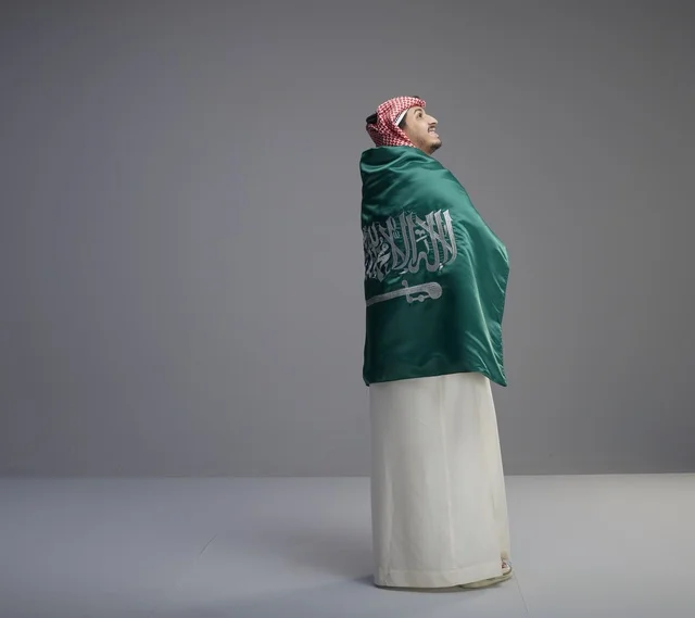 رجل سعودي يلتف بعلم السعودية في الاستوديو