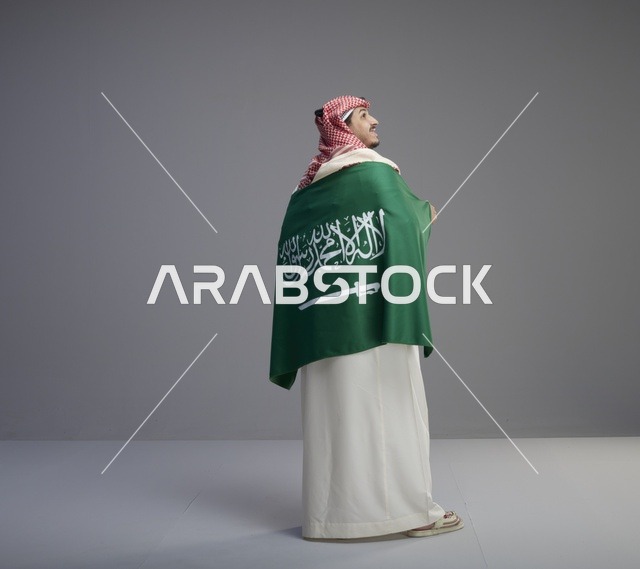 رجل سعودي مع العلم الوطني على خلفية رمادية