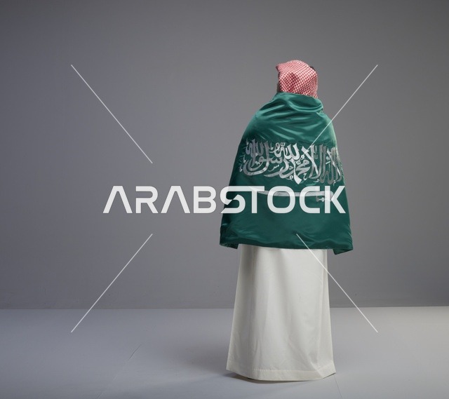 رجل سعودي يلتف بعلم المملكة العربية السعودية