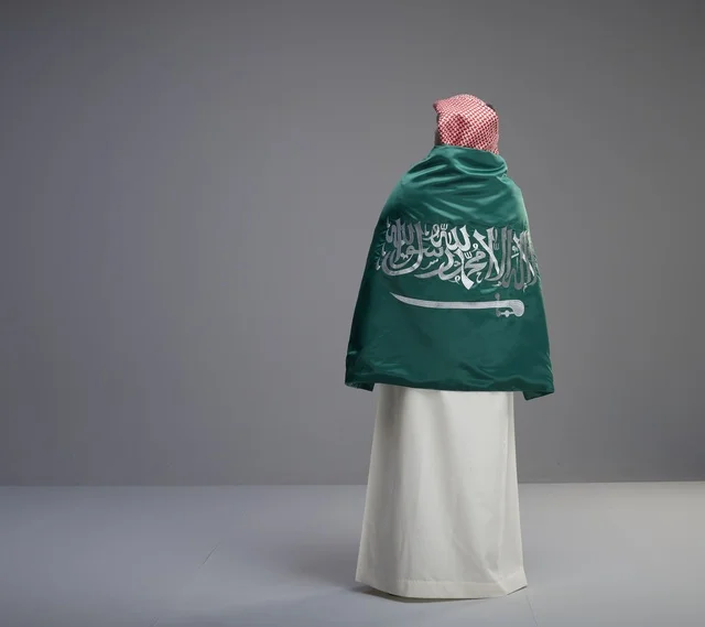 رجل سعودي يلتف بعلم المملكة العربية السعودية