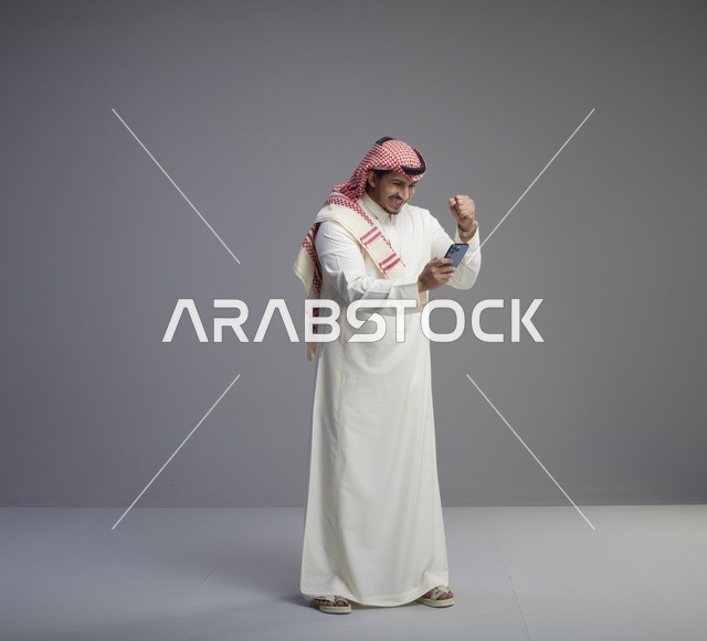 رجل سعودي يحتفل بالنجاح باستخدام الهاتف الذكي