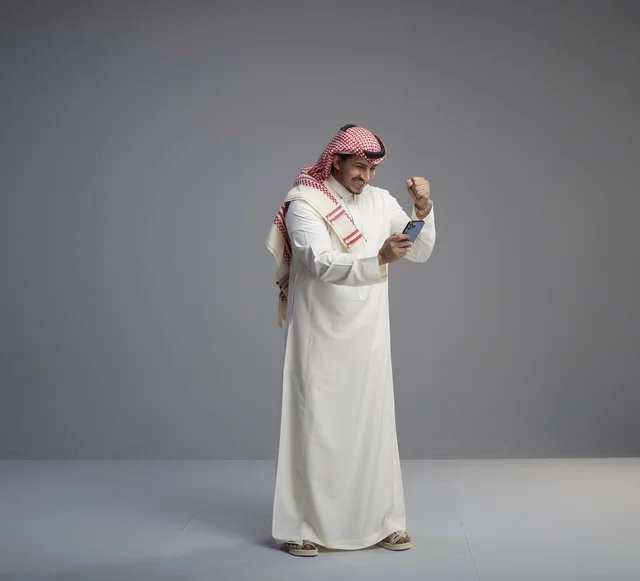 رجل سعودي يحتفل بالنجاح باستخدام الهاتف الذكي